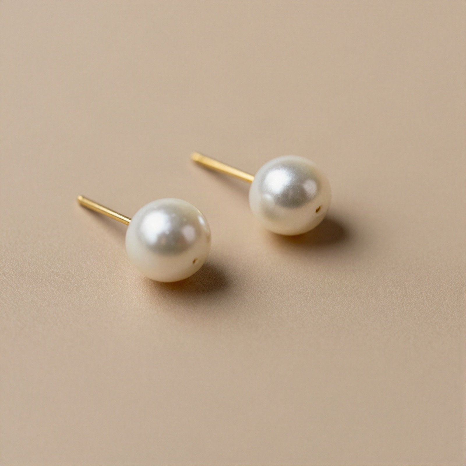A pair of white pearl stud earrings on gold posts