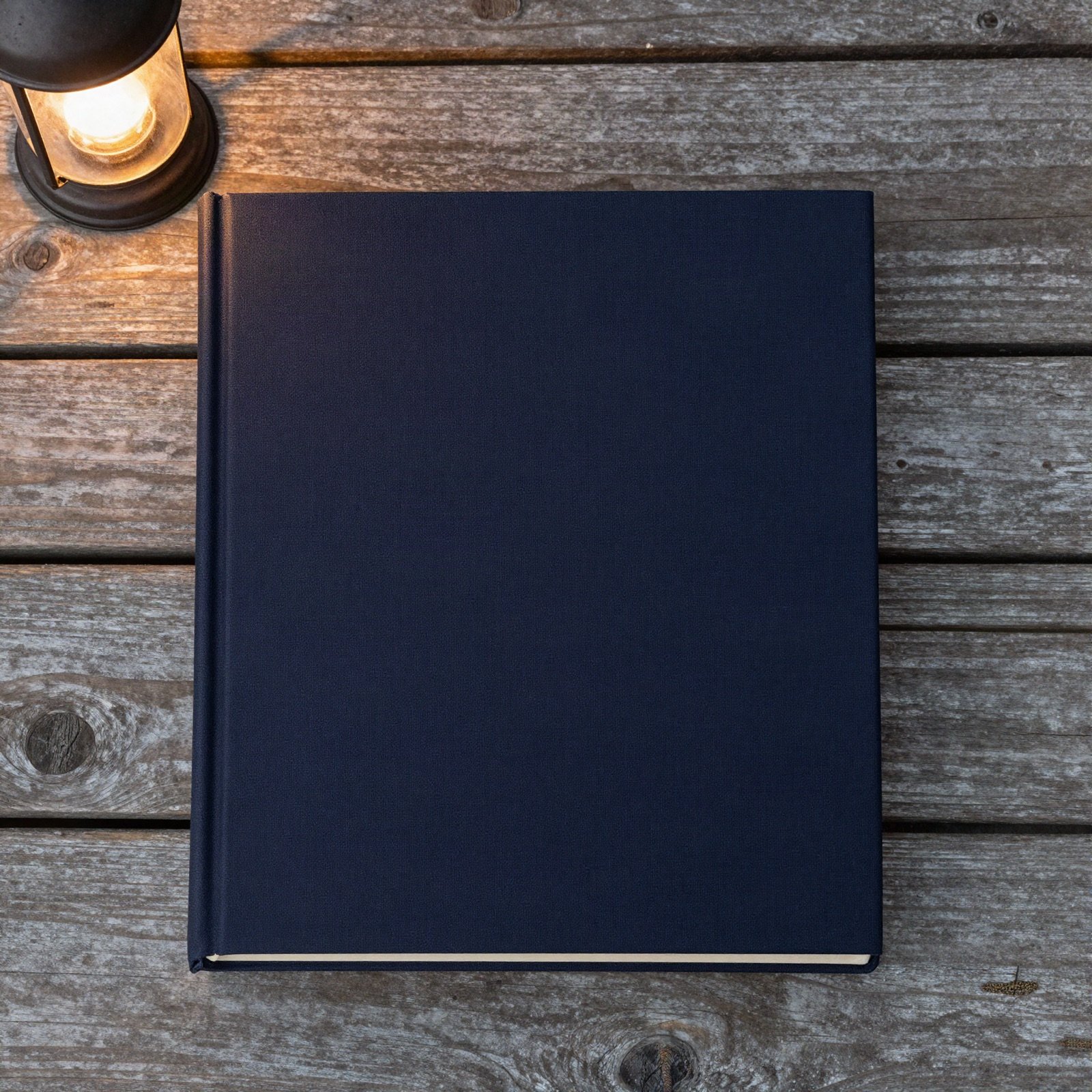 كتاب بغلاف مقوى كحلي على ألواح شرفة قديمة بجانب فانوس مضاء